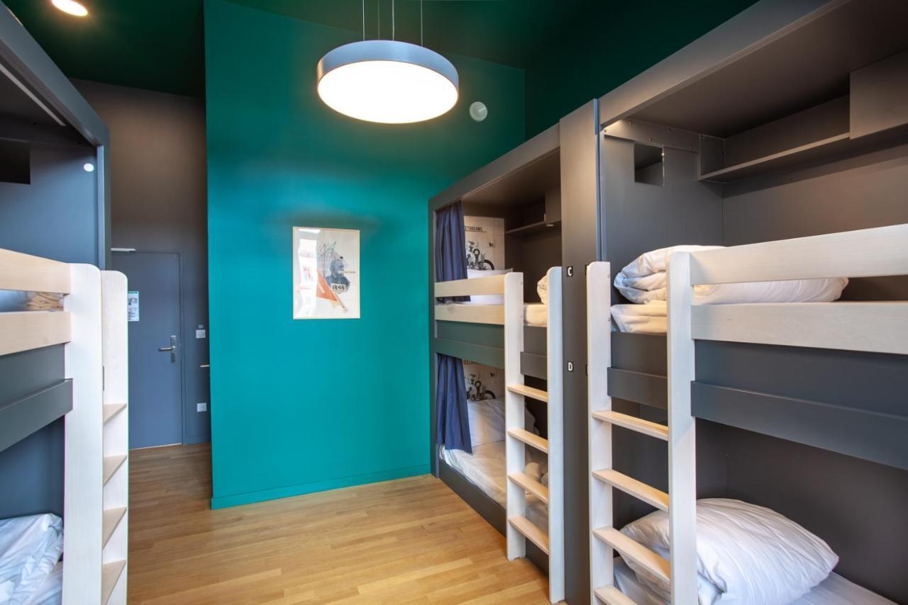 The People - Strasbourg Hostel Εξωτερικό φωτογραφία The photo shows an interior of a room designed for sleeping accommodation, likely a hostel or shared lodging. The walls are painted a vibrant green, which adds a modern touch. On one side, there are two sets of bunk beds made of light-colored wood, w