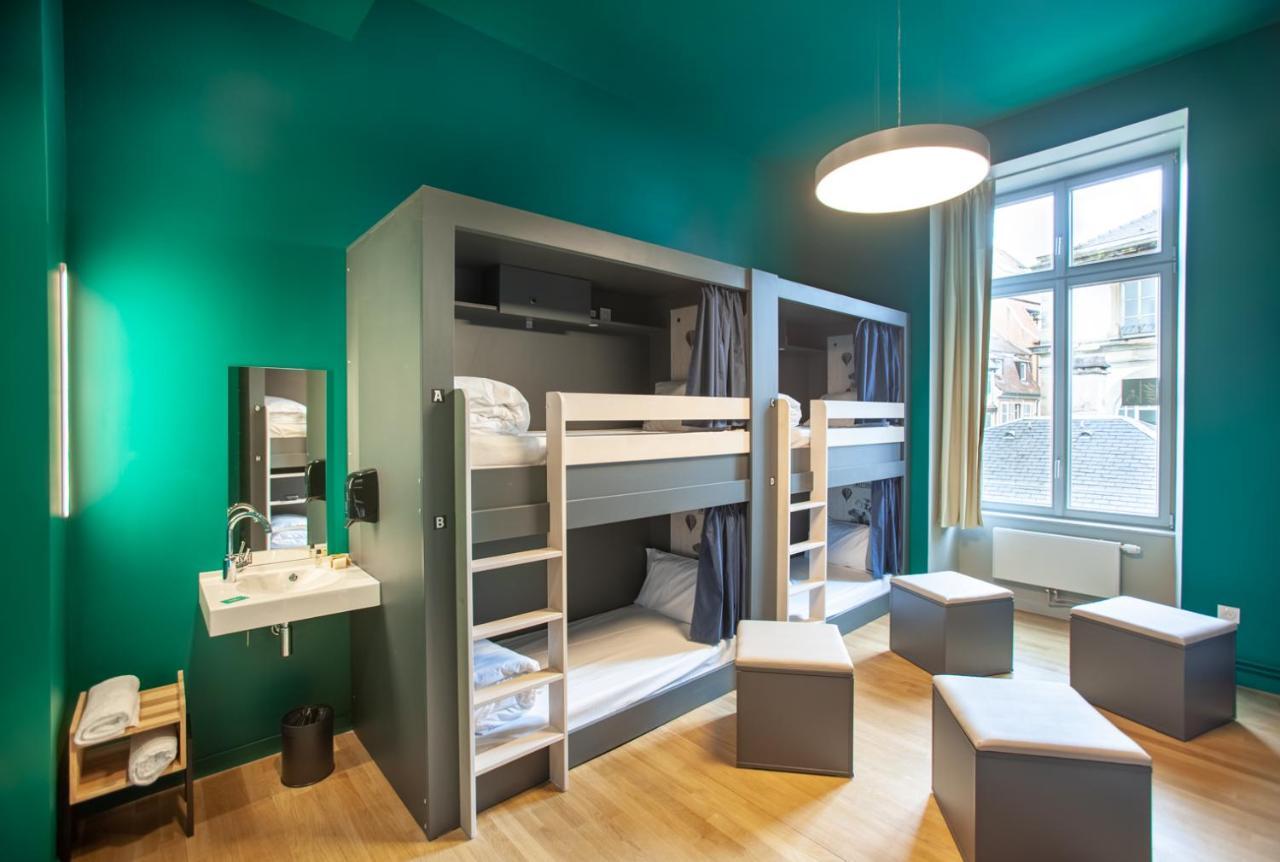 The People - Strasbourg Hostel Εξωτερικό φωτογραφία The photo shows a modern dormitory room with a vibrant teal wall color. There are two sets of bunk beds, each equipped with ladder access and privacy curtains. Next to the beds, there’s a small sink and a mirror mounted on the wall. The room features