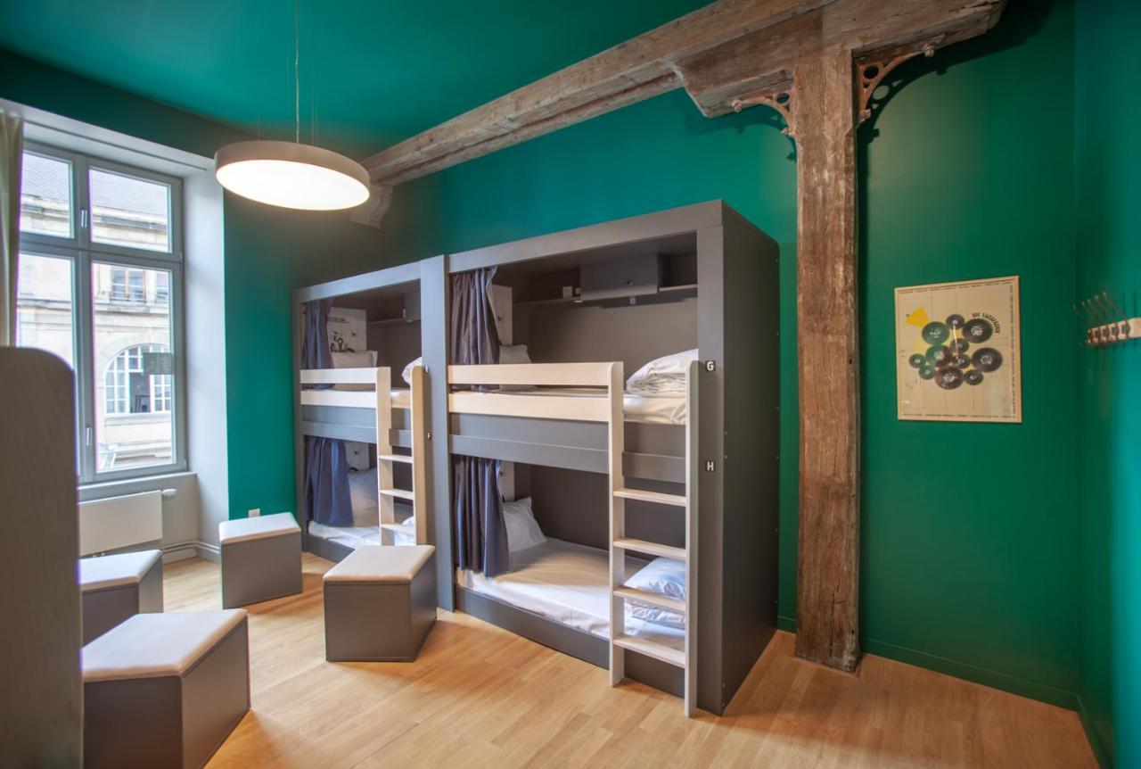 The People - Strasbourg Hostel Εξωτερικό φωτογραφία The photo shows a modern and stylish dormitory-style room. The walls are painted a vibrant green color, creating a lively atmosphere. There are two sets of bunk beds along one wall, each with storage space underneath and curtains for privacy. The bed