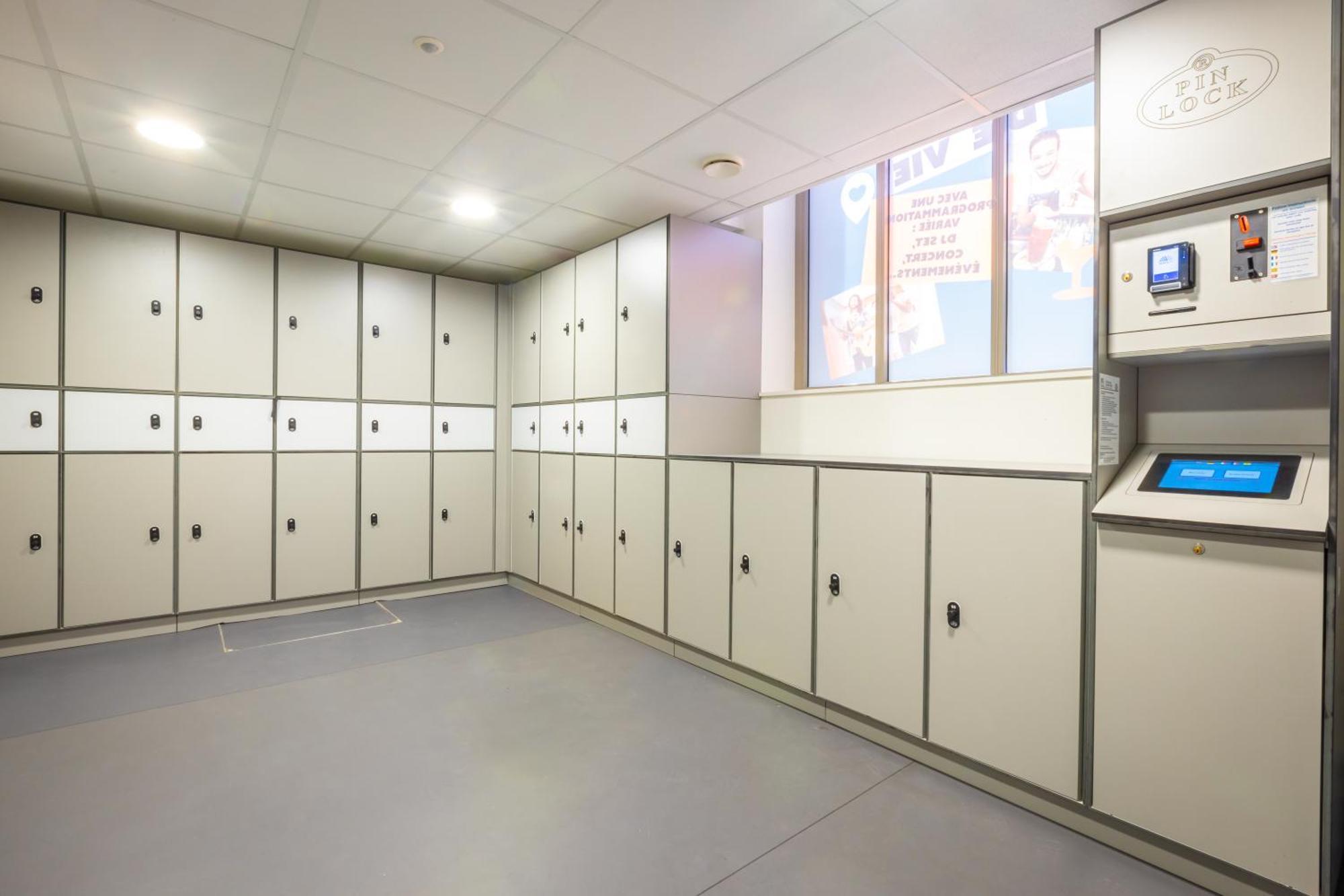 The People - Strasbourg Hostel Εξωτερικό φωτογραφία The photo shows a room with several storage lockers arranged along the walls. The lockers are predominantly white with simple silver handles. There is a payment or control kiosk on the right side, featuring a digital screen and buttons for user inter