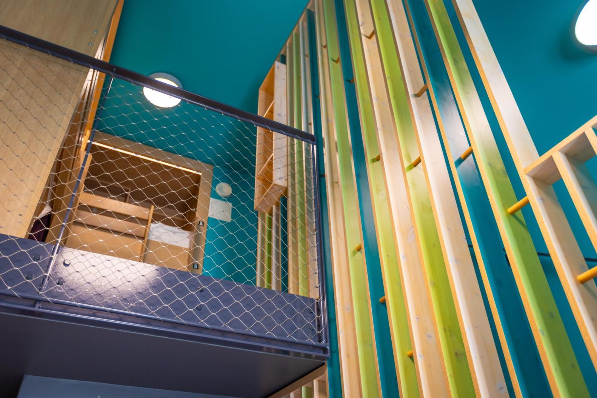 The People - Strasbourg Hostel Εξωτερικό φωτογραφία The photo shows an interior space with a modern design featuring a vibrant color scheme. There's a mesh railing that indicates a two-level structure, possibly a loft or mezzanine. The walls are adorned with vertical wooden slats in various shades of 