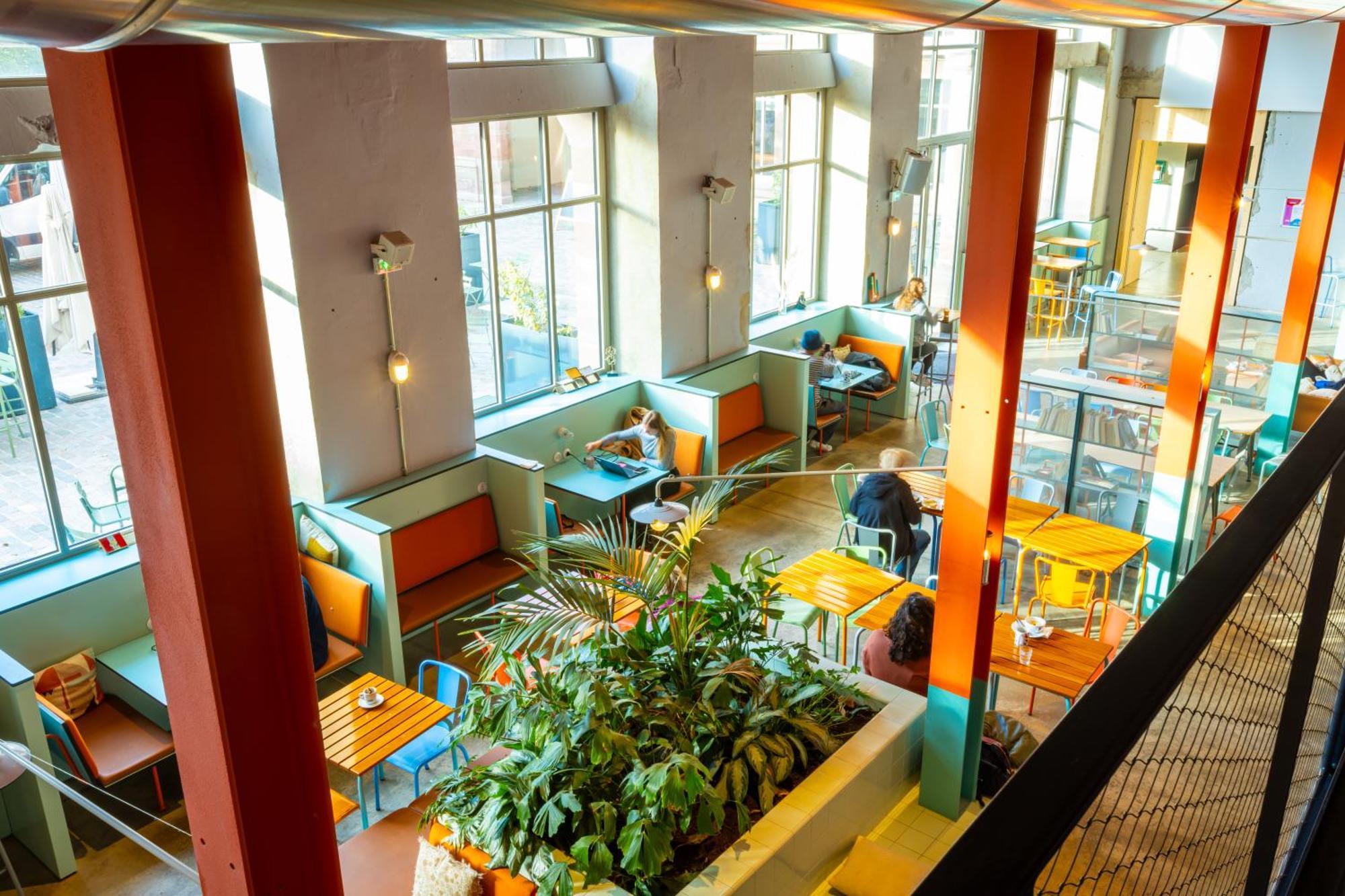 The People - Strasbourg Hostel Εξωτερικό φωτογραφία The photo shows a bright and modern cafe or restaurant interior. It features large windows that allow natural light to fill the space, which is decorated with colorful seating arrangements. There are various tables, some with wooden surfaces, and com