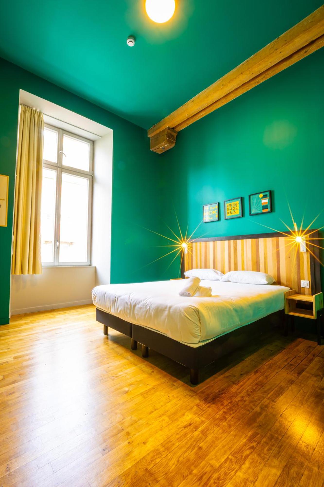 The People - Strasbourg Hostel Εξωτερικό φωτογραφία The photo shows a cozy bedroom featuring a double bed with white linens and a couple of towels placed on it. The walls are painted a vibrant teal color, creating a lively atmosphere. There are two framed artworks hanging above the bed, adding a touch
