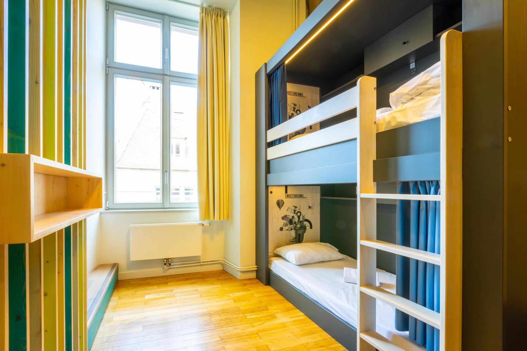 The People - Strasbourg Hostel Εξωτερικό φωτογραφία The photo shows a modern and cozy room designed for sleeping or accommodation. It features a bunk bed with a top and bottom sleeping area. The bottom bunk has a mattress and is partially enclosed by curtains for privacy. There is a small ladder for e