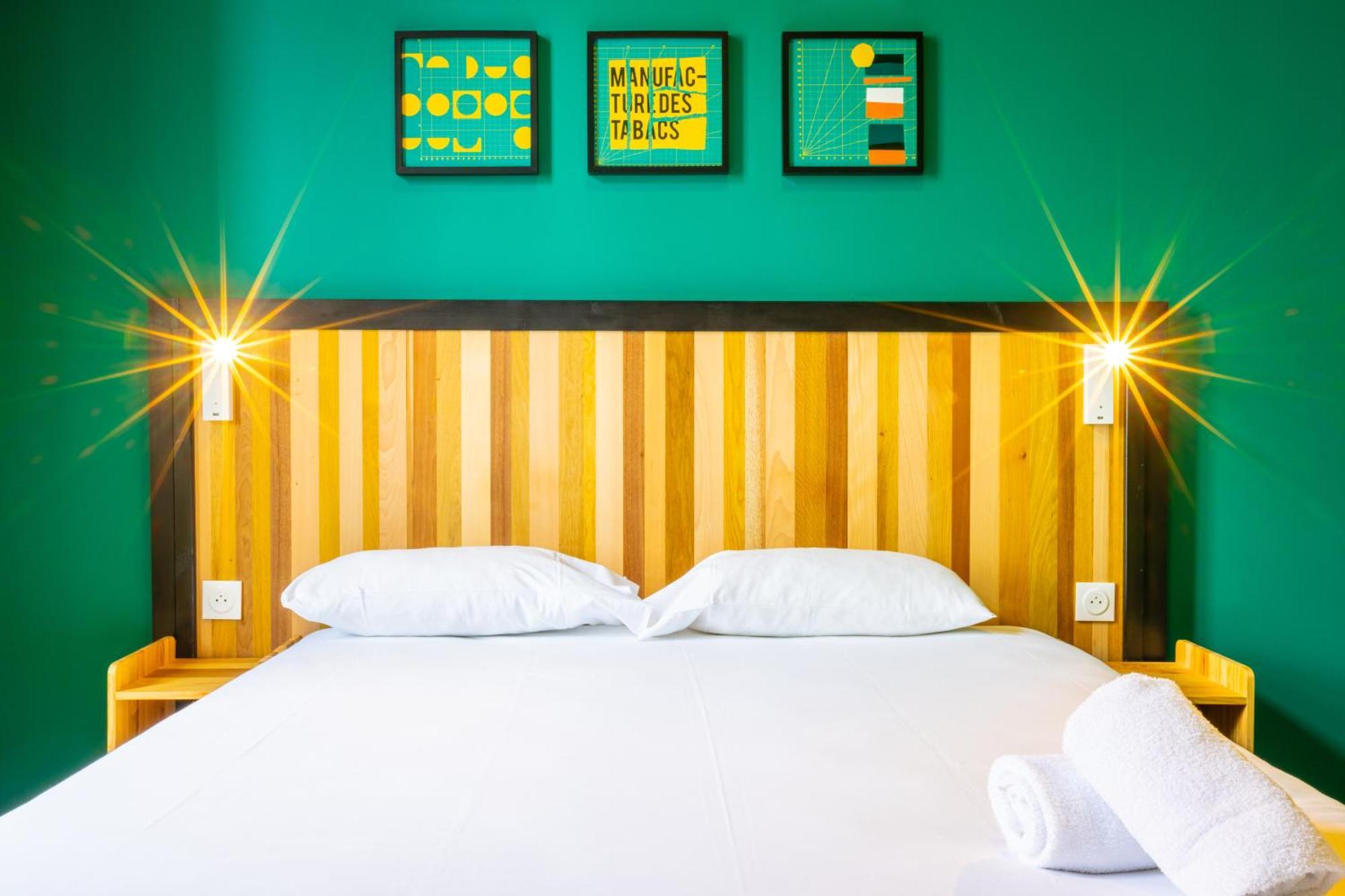 The People - Strasbourg Hostel Εξωτερικό φωτογραφία The photo shows a modern bedroom. The walls are painted a vibrant green, creating a lively atmosphere. In the background, there are four framed artworks displayed above the bed. The bed features a wooden headboard with a striped design, and there are