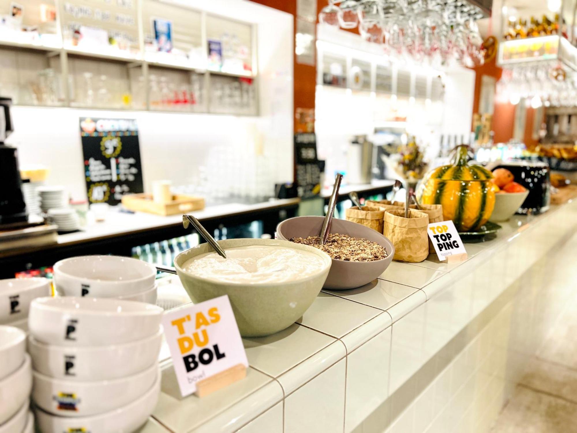 The People - Strasbourg Hostel Εξωτερικό φωτογραφία The photo shows a buffet or dining area with a variety of food items. There are several bowls containing what appears to be yogurt or a similar creamy substance, alongside granola or cereal. The bowls are placed on a countertop, which is white and ha